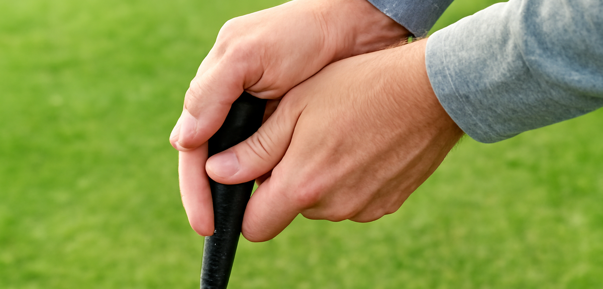 Close-up of hands gripping a golf club handle on grass, photorealistic, no text